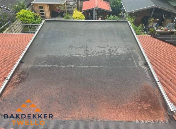 Verouderd plat dak met slijtage tussen schuine daken in Twello Verouderd plat dak met slijtage tussen schuine daken in Twello