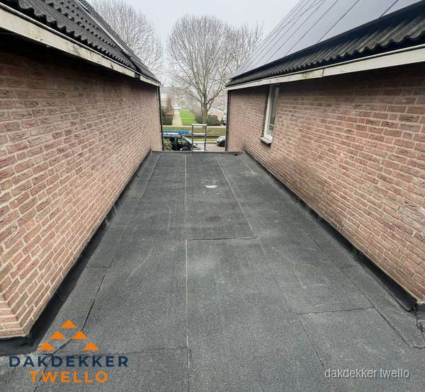 Plat dak met bitumen dakbedekking tussen bakstenen muren in Twello Plat dak met bitumen dakbedekking tussen bakstenen muren in Twello